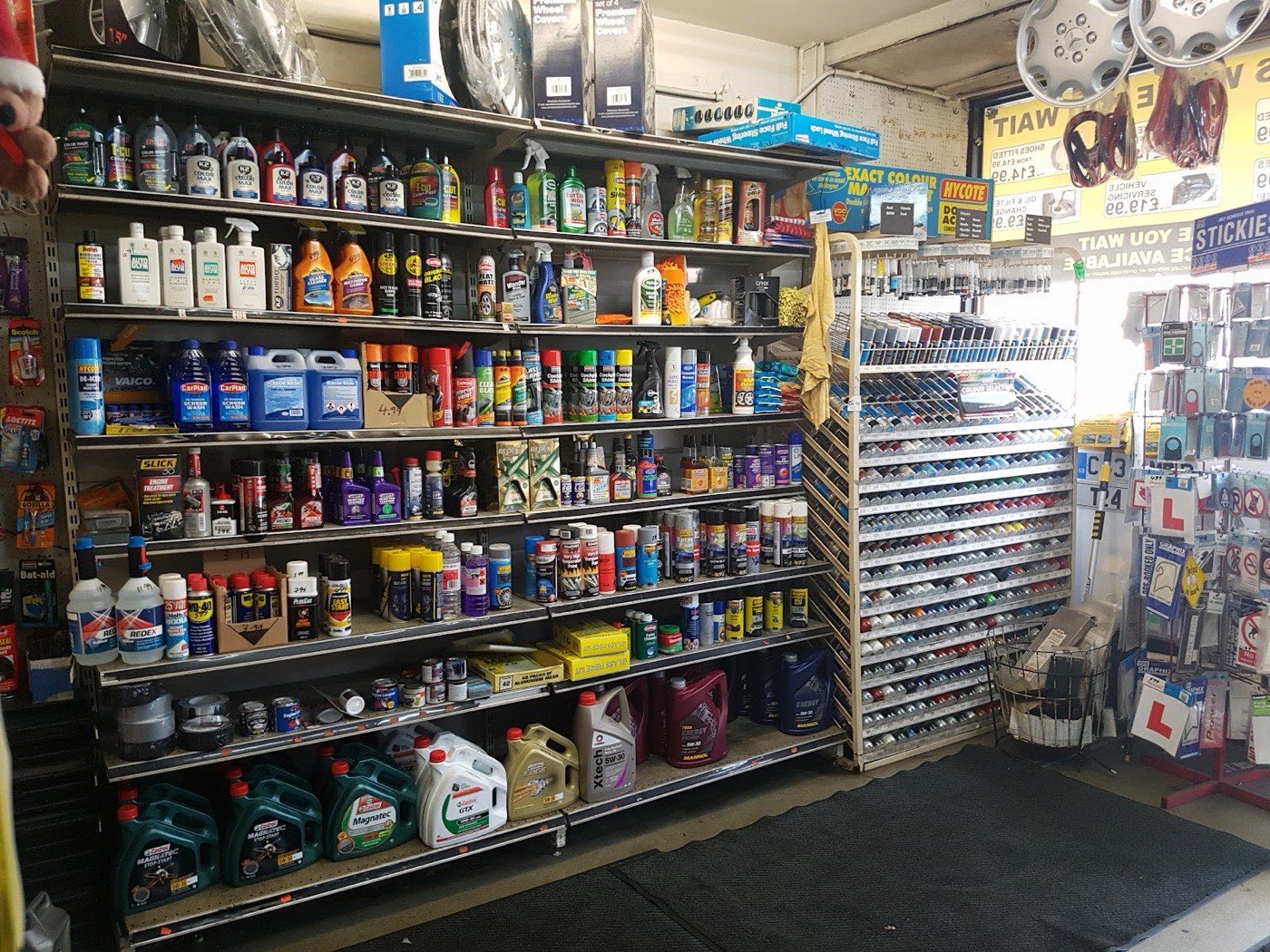 Floor-to-ceiling shelves of car care products, oils, screen wash, touch-up paint and a colour-match paint rack inside the Ranic Motors spares shop.