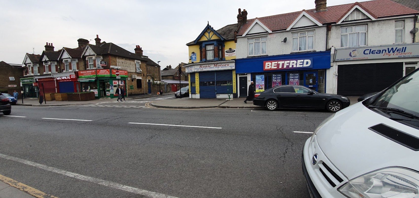 Wide view of High Street South, East Ham, showing the Ranic Motors shopfront among the local parade of shops.